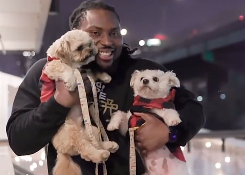 Football player Derrick Nnadi holds two small dogs at his dog rescue event.